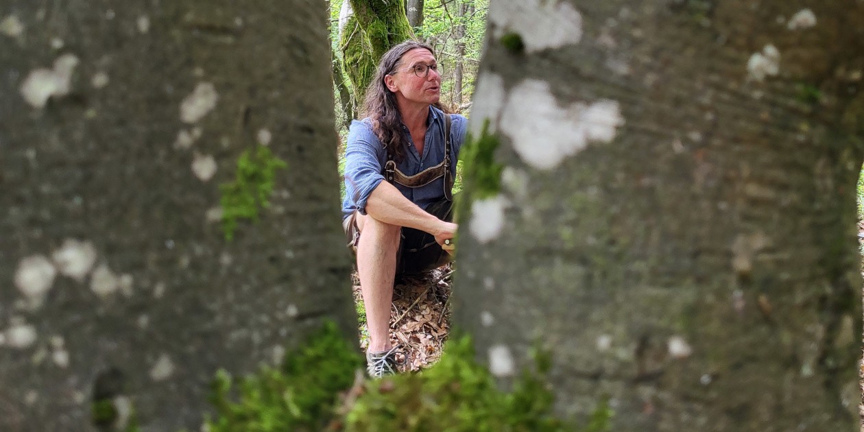 Das Engelsauge, gebildet von einem sich teilenden Baum. Durch das Auge ist Jürgen Franz Oswald bei einer spirituellen Waldspaziergang zu sehen.